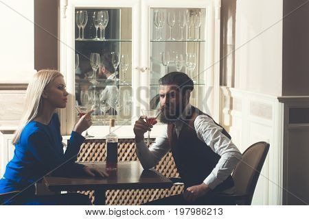 Man and woman drinking from martini glasses. Hipster and girl sharing bottle of wine in restaurant. Couple in love. Alcohol appetizer addictive and convive. Unhealthy lifestyle. Bad habits