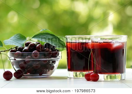 Two glasses of cherry juice with ice on a green background