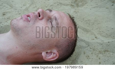 a young man lies on the sand on the beach.