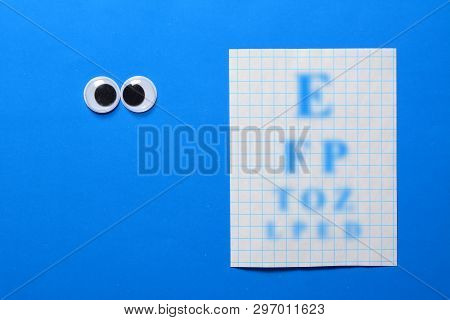 Cross-eyed Googly Eyes On Blue Background With Sight Check Table. Mad Funny Toys Eyes Close Up.