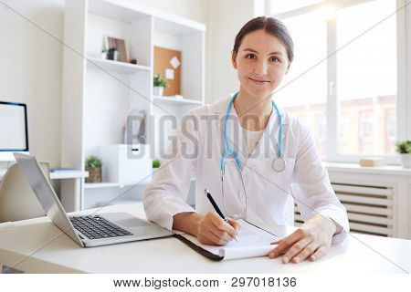 Portrait Of Young Female Doctor Smiling At Camera While Working In Office, Copy Space