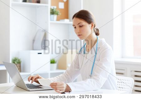 Portrait Of Young Female Doctor Using Laptop While Working In Office, Copy Space