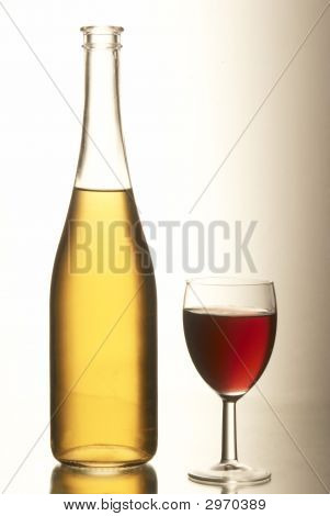 gelbe Flasche Rotwein mit einer vollständigen Becher.