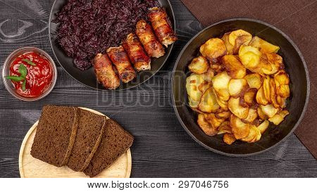 Roasted Potato In The Pot, Pieces Of Rye Black Bread On A Wooden Serving Plate, Homemade Sausages In