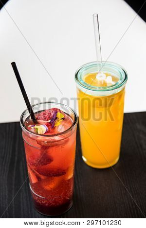 fresh lemonade with  straws with fresh strawberry and orange on a bar table