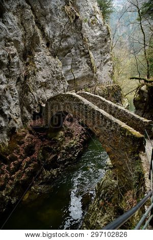 Stone Bridge Through A River In Switzerland