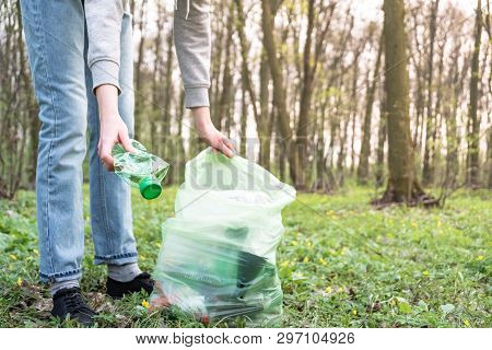 Cleaning-up The Forest Of Plastic Garbage. Person Picks Up A Plastic Bottle In The Woods, Concept Of