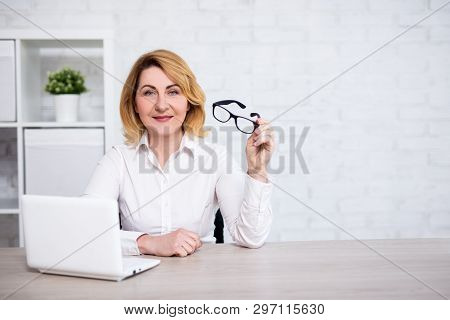 Mature Business Woman Sitting With Laptop In Modern Office Or Living Room - Copy Space Over White Br