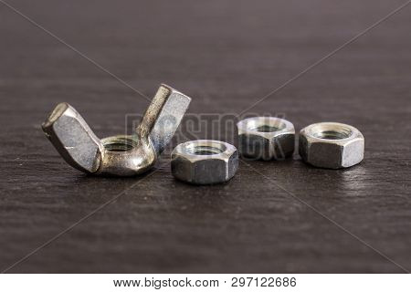 Group Of Four Whole Work Item One Metal Wingnut And Three Locking Nuts On Grey Stone