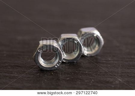 Closeup Of Three Whole Metal Locking Nuts Work Item On Grey Stone