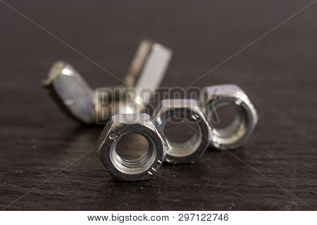 Group Of Four Whole Metal Work Item One Wingnut And Three Locking Nuts On Grey Stone
