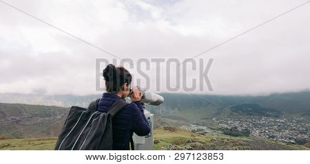 Young Tourist Woman Looking Through Coin Operated High Powered Binoculars On The Caucasus Mountains,