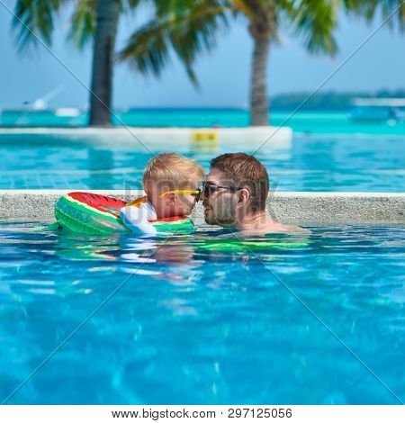 Three year old toddler boy in resort swimming pool eskimo kissing his father. Summer family vacation at Maldives.