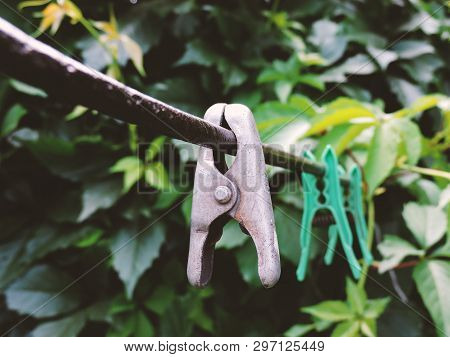 Linen Clothespins In The Yard. Plastic Linen Clothespin On Old Rope On Green Background. Many Multi-