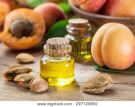 Apricot kernel oil and apricot kernels on wooden background.