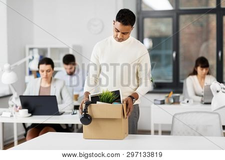 business, firing and job loss concept - sad fired indian male office worker with box of his personal stuff