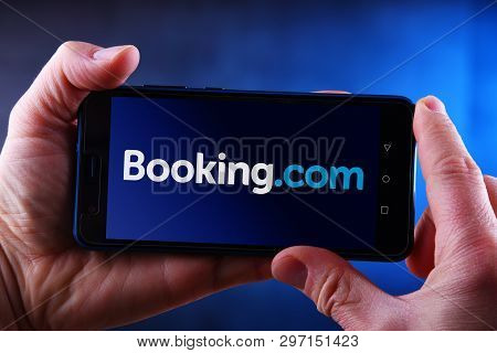 Poznan, Pol - Mar 24, 2019: Hands Holding Smartphone Displaying Logo Of Booking.com, A Travel Fare A