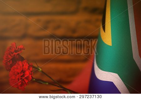 South Africa Flag With Two Red Carnation Flowers For Honour Of Veterans Or Memorial Day On Orange Bl