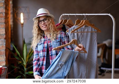 Pretty Young Woman In Hat And Glasses Is Choosing New Outfit For Summer In Modern Butique. She Wear 