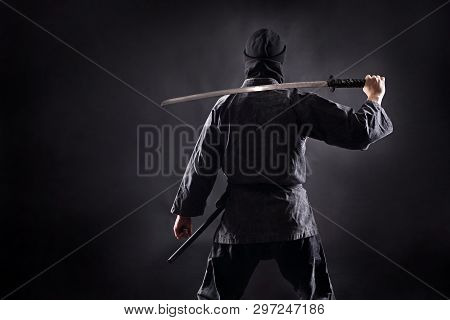 Ninja Samurai With Katana Stands With His Back To The Viewer.