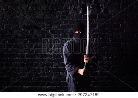 Ninja Samurai With Katana In Attack Pose On A Dark Brick Wall Background