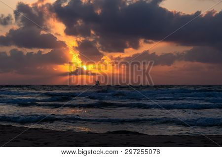 A Lone Ship Sails Into The Sea Towards The Setting Sun.