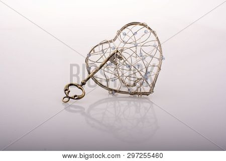 Key And A Heart Shaped Metal Cage On White
