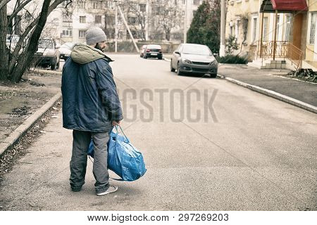 Poor Homeless Man With Bag On City Street