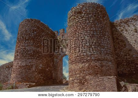 Stone Thick Towers In A Sunny Day Beside The Entrance Doorway On The Outer Wall Of Evoramonte. A Tin
