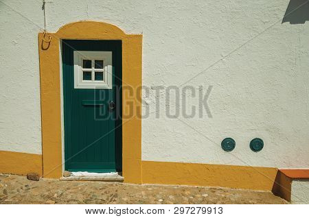 Green Wooden Door In A White Wall On Sunny Day, From A Cobblestone Street Of Evoramonte. A Tiny Fort