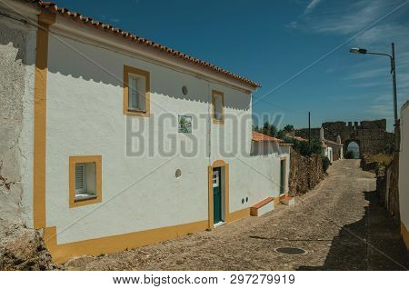 Green Wooden Doors In White Wall House On Sunny Day, From A Cobblestone Street Of Evoramonte. A Tiny