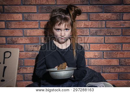 Poor Little Girl With Bread Against Brick Wall