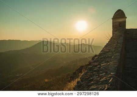 Small Watchtower And Stone Wall Over Rocky Cliff, With Hilly Landscape And Sunset Glow At Marvao. An