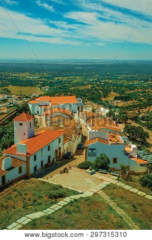 Evoramonte, Portugal - July 06, 2018. Village main street with green hills at Evoramonte. A tiny fortified civil parish over hill where stands out its historic castle in Portugal. Retouched photo.