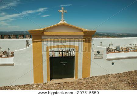 Evoramonte, Portugal - July 6, 2018. Colorful gateway in graveyard wall in the main street of Evoramonte. A tiny fortified civil parish over hill where stands out its historic castle in Portugal.