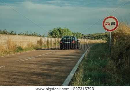Elvas, Portugal - July 06, 2018. NO OVERTAKING traffic sign and car passing by a countryside road near Elvas. A gracious star-shaped fortress city on the easternmost frontier of Portugal.