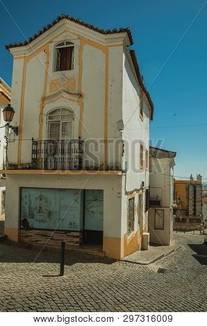 Elvas, Portugal - July 07, 2018. Alley with old colorful house facade and deserted causeway on sunny day at Elvas. A gracious star-shaped fortress city on the easternmost frontier of Portugal.