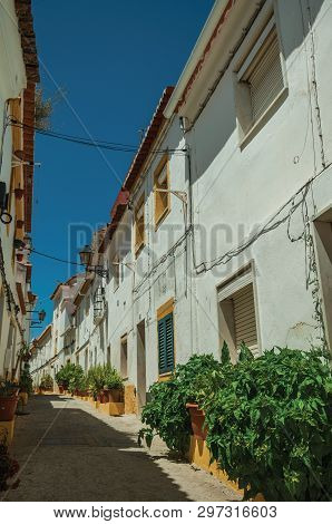 Elvas, Portugal - July 7, 2018. Old colorful houses with flowered vases and deserted causeway in a narrow alley at Elvas. A gracious star-shaped fortress city on the easternmost frontier of Portugal.