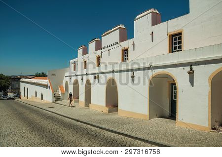 Elvas, Portugal - July 7, 2018. Little girl walking on sidewalk next to whitewashed building with arches in Elvas. A gracious star-shaped fortress city on the easternmost frontier of Portugal.