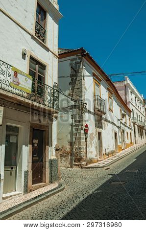 Elvas, Portugal - July 7, 2018. Old terraced houses with peeling plaster and deserted causeway in an alley at Elvas. A gracious star-shaped fortress city on the easternmost frontier of Portugal.