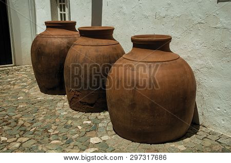 Campo Maior, Portugal - July 8, 2018. Large Earthenware Vessels Over Floor And Rough Plaster Wall At