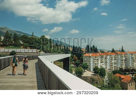 Covilha, Portugal - July 11, 2018. Woman And Child Walking On Footbridge Over Valley With Building A