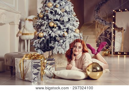 Happy Young Lady With Curlu Hair Gifts By The Fireplace Near The Christmas Tree. New Year Concept.