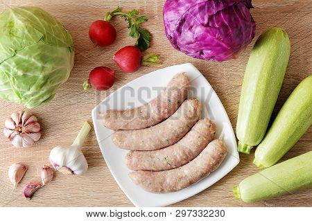 Raw Meat Sausages Kupaty And Vegetables - Cabbage, Zucchini, Radish And Garlic On Wooden Background