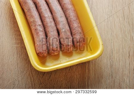 Raw Meat Sausages Kupaty In The Yellow Plastic Tray On Wooden Background