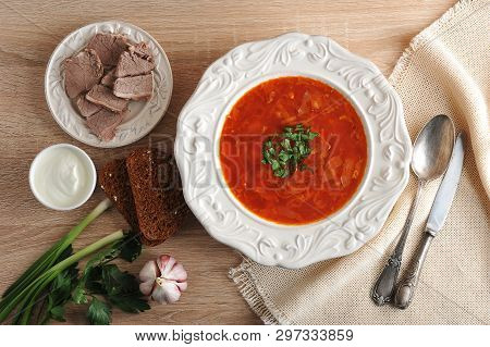 Soup In A Bowl With Dill, Sour Cream, Beef And Black Bread On Wooden Background - Top View - Borsh -
