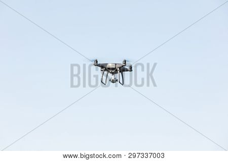 Flying Drone On The Blue Sky. Modern Silver Drone Flying.