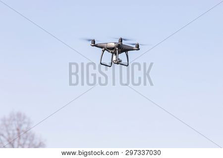 Flying Drone On The Blue Sky. Modern Silver Drone Flying.