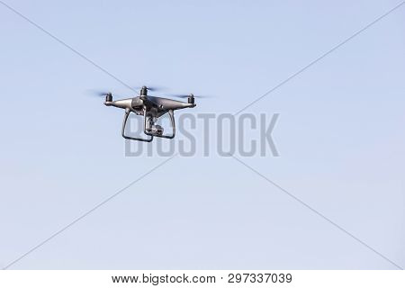 Flying Drone On The Blue Sky. Modern Silver Drone Flying.