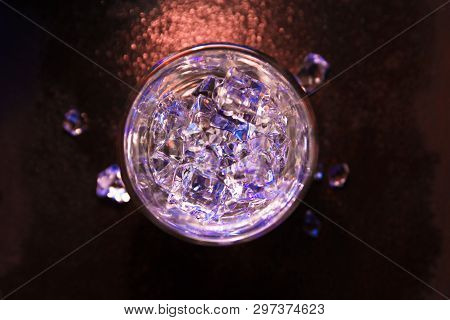 Glass Of Pure Water With Ice Cubes. View From Above. Abstract Dynamic Backdrop For Your Design